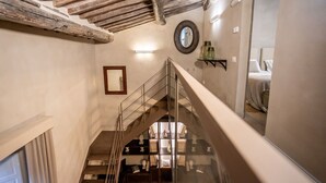 A staircase with a glass railing leading to a bedroom with a bed and a bedside table. - Apartment in Cortona with 2 bedrooms sleeps 4 (Cortona)