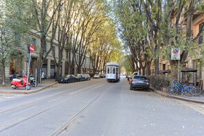 Een straat met een tram, geparkeerde auto's en fietsen.