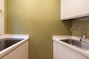A compact kitchen with a built-in stove, a stainless steel sink, and white cabinetry. - Luxury 2BR Apt · Steps from Last Supper & Parco Sempione · Milan (Milano)