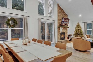 A spacious living room with a fireplace, a dining area with a long table, and a cozy seating area. - 6BR Poconos Retreat, Hot Tub, Game Room, Fire Pit (Blakeslee)