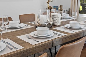 A dining table set with white plates, bowls, and wine glasses, with a decorative centerpiece of antlers and a candle. - 6BR Poconos Retreat, Hot Tub, Game Room, Fire Pit (Blakeslee)