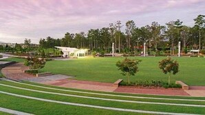 A well-maintained park with a grassy area, pathways, and a small building with a white roof.