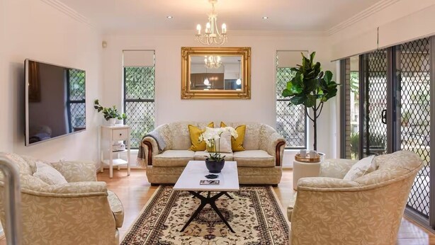 A living room with a sofa, armchairs, a coffee table, and a TV.
