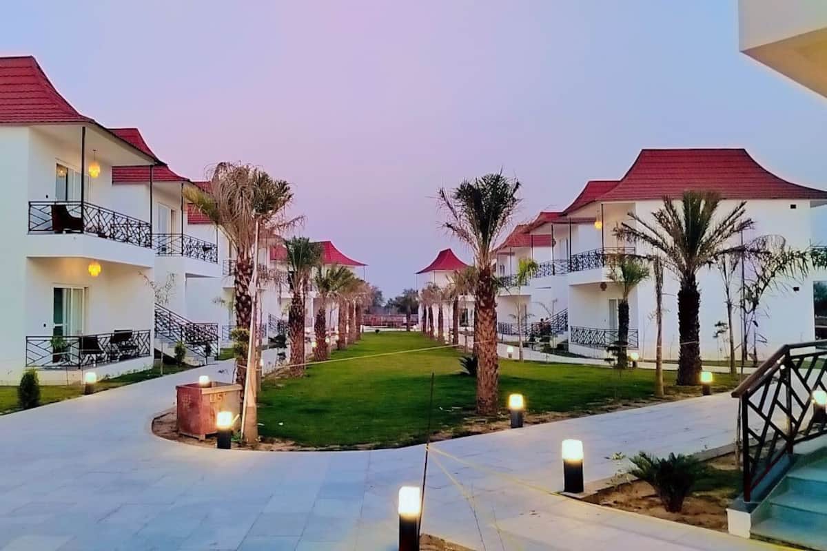 A hotel corridor with white buildings, red roofs, and palm trees.