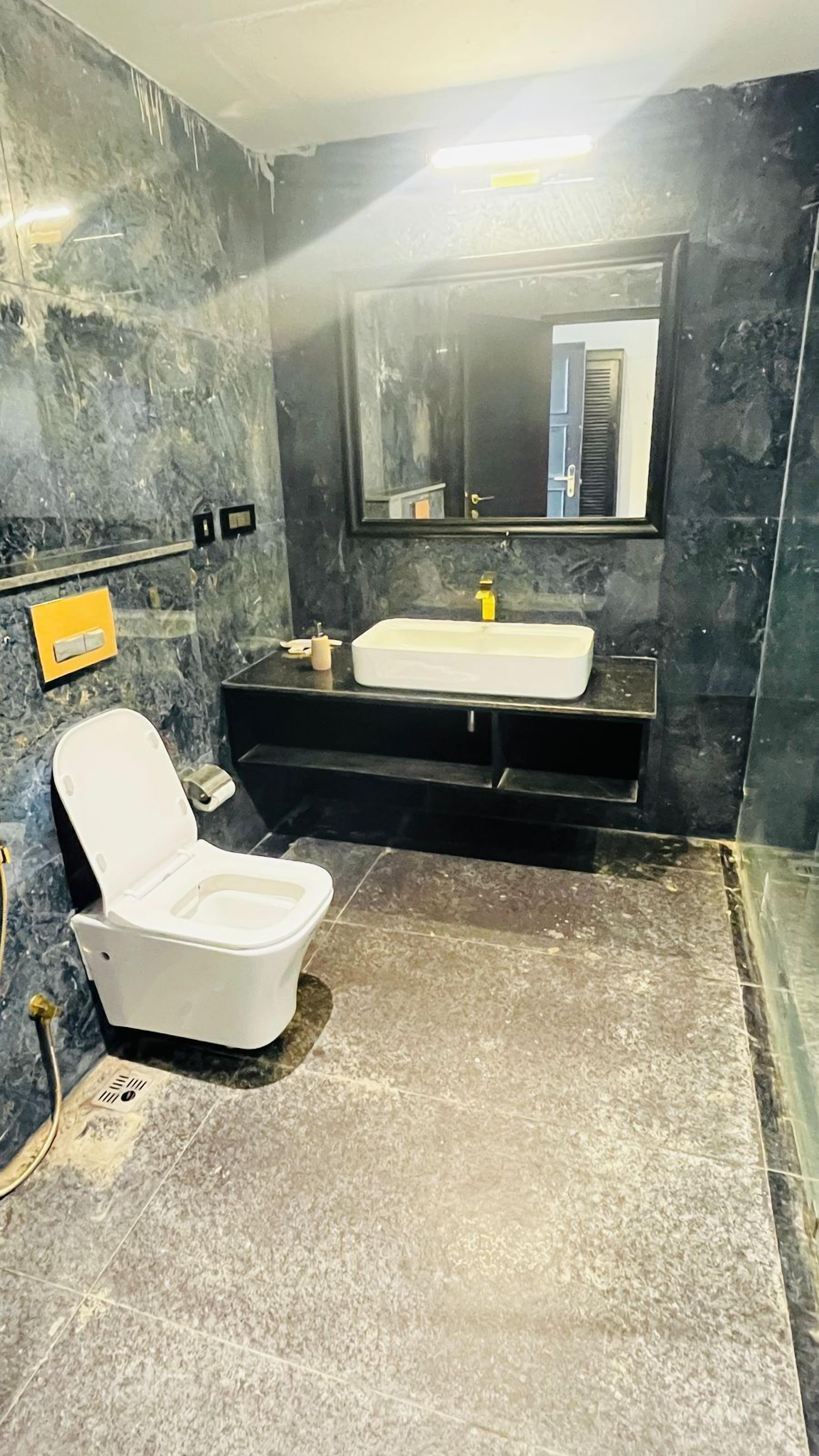 Un baño con inodoro blanco, lavamanos y espejo.