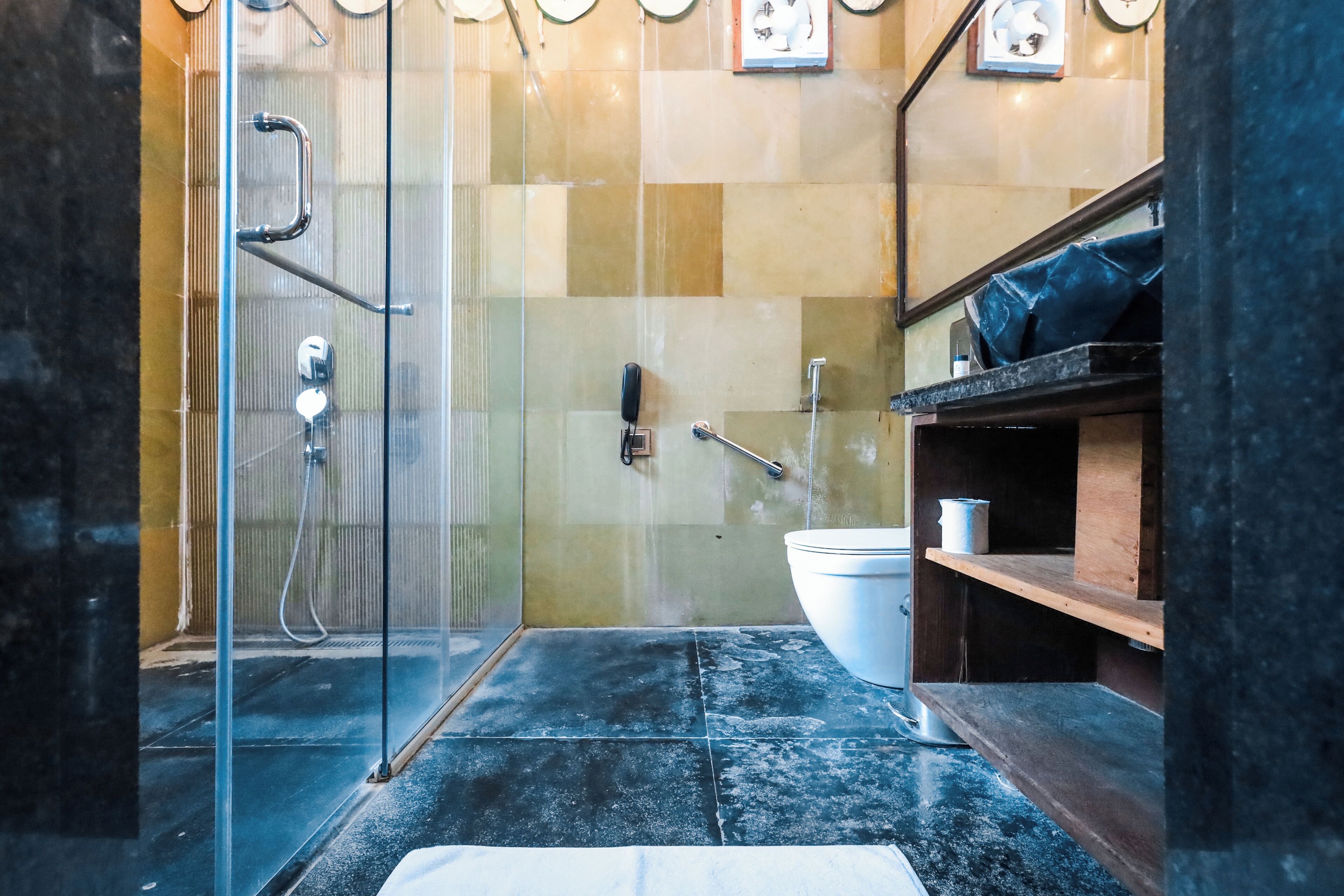 A modern bathroom with a glass-enclosed shower, a white sink, and a wooden shelf.