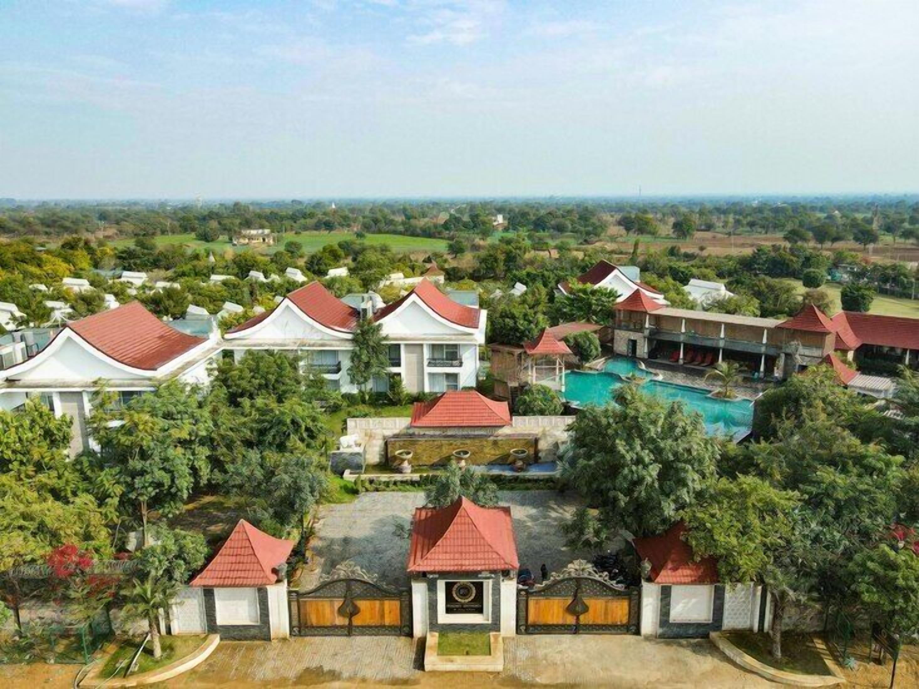 A resort with multiple buildings, a swimming pool, and lush greenery.