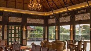 A spacious dining area with a high ceiling and a chandelier, featuring a large table and several chairs. - Estherea Resort and Spa, Jaipur (Bassi)
