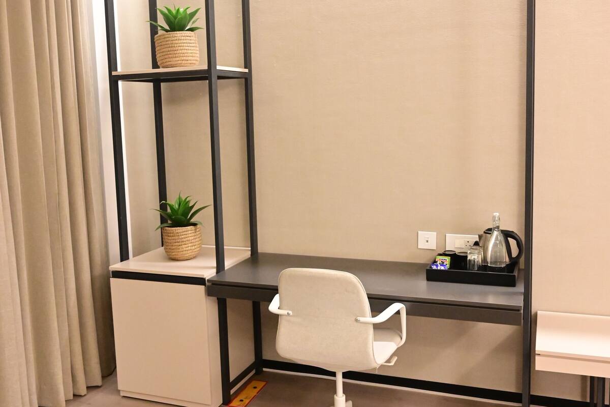 Un espacio de oficina moderno con un escritorio, una silla y una estantería con plantas en macetas.