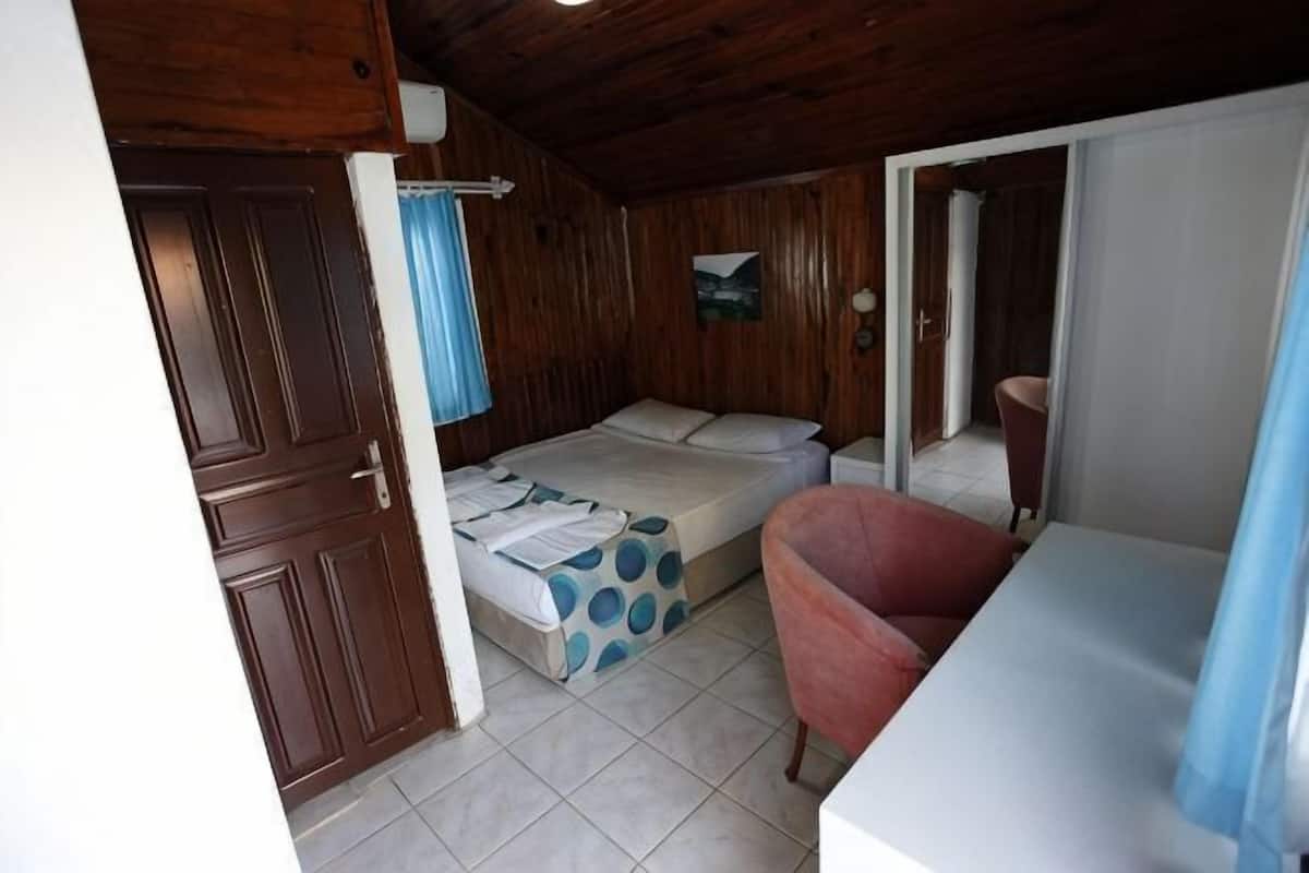 Una habitación con una cama, una silla, un escritorio y una puerta.