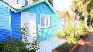 A row of colorful houses with white doors and windows, a garden area with plants, and a paved walkway. - Cuba Beach Hotel (Manavgat)