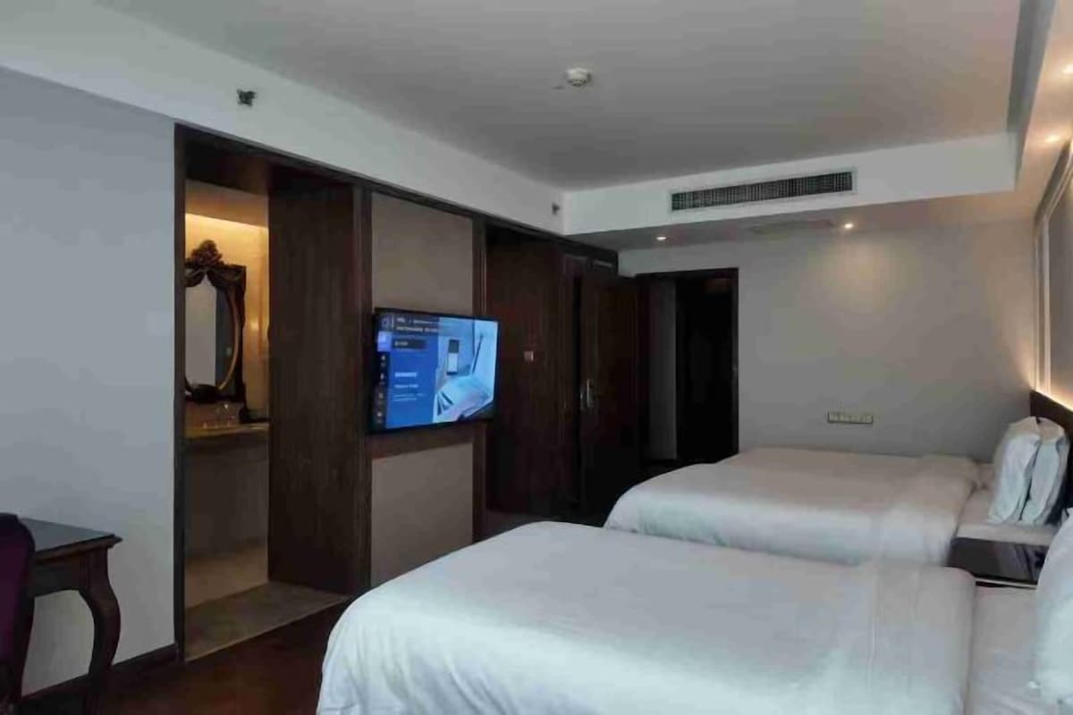 A hotel room with two beds, a television, and a wardrobe.
