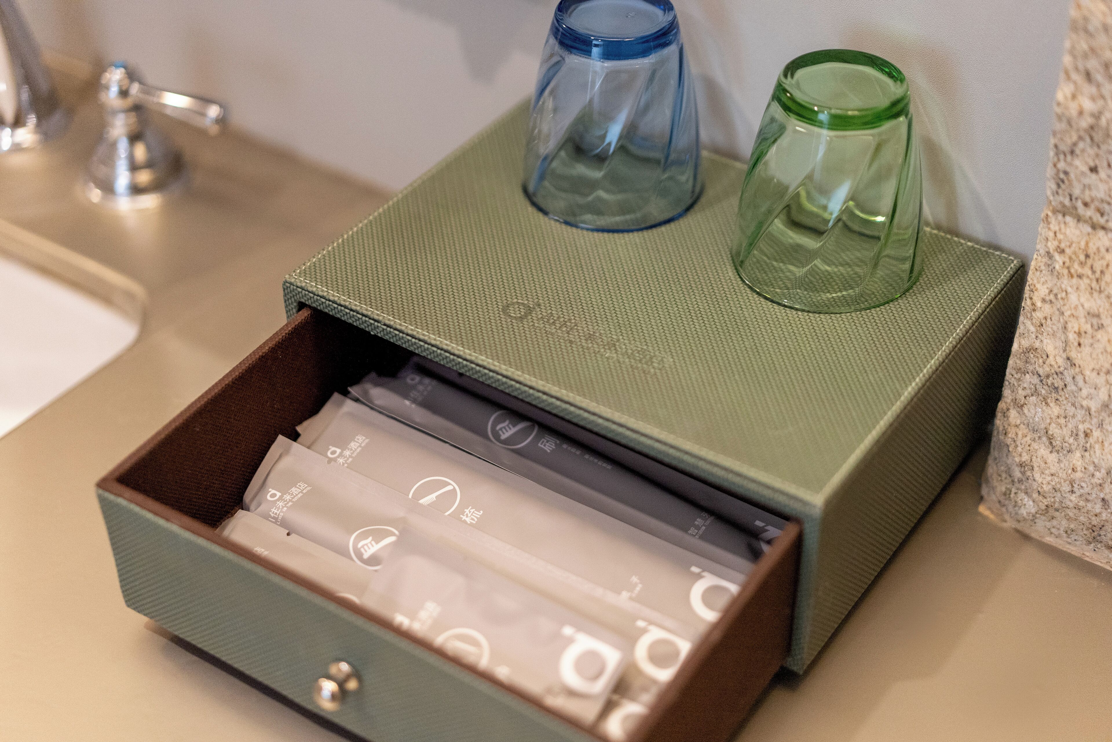 A green box with a drawer containing several items, including a green and a blue glass.