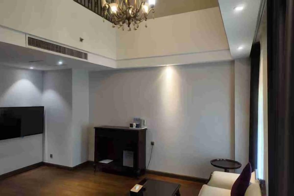 A spacious living room with a flat-screen TV, a small table, and a sofa.