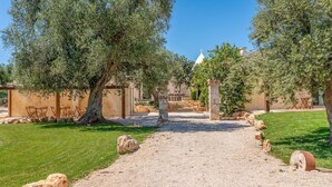 A gravel pathway leading to a building with outdoor seating and stone pillars.