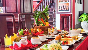 Una mesa de comedor dispuesta con diferentes platos, como arroz, verduras y pan, junto con bebidas y una planta decorativa en el centro.