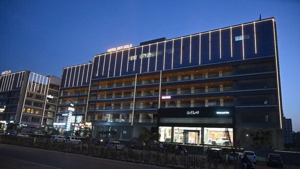 A multi-story hotel with a modern facade, balconies, and a visible restaurant. - HOTEL SKY GOLD (Gandhinagar)