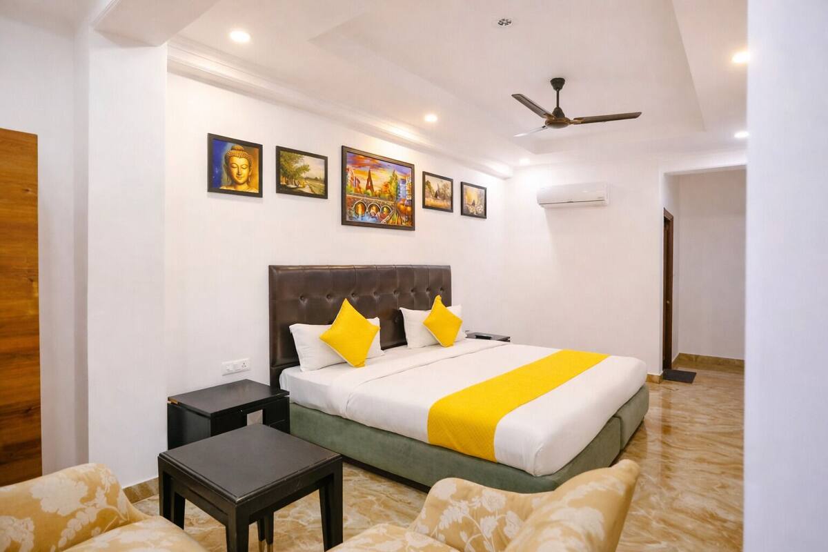 Quarto de hotel com uma cama grande, mesa de cabeceira, uma pequena mesa e um ventilador de teto.