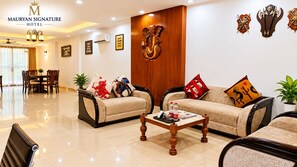 Un vestíbulo de hotel con sofás, una mesa de centro, decoración en la pared y un mostrador de recepción.