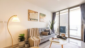 Una sala de estar moderna con un sofá gris, una lámpara de pie, una mesa de centro y dos cuadros abstractos en la pared.