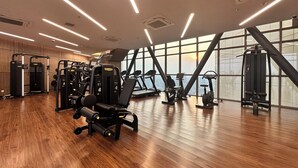 Un gimnasio con equipo de ejercicio, ventanas amplias y suelo de madera.