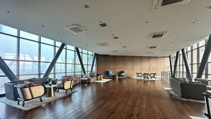 Una habitación amplia con ventanas grandes, suelo de madera y mobiliario moderno.