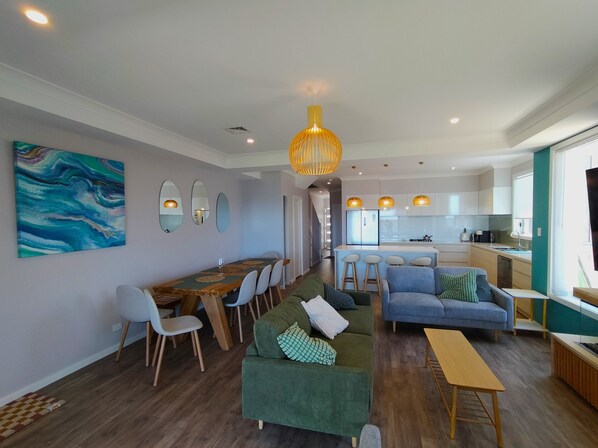 Una sala de estar moderna con comedor, cocina y un amplio ventanal.