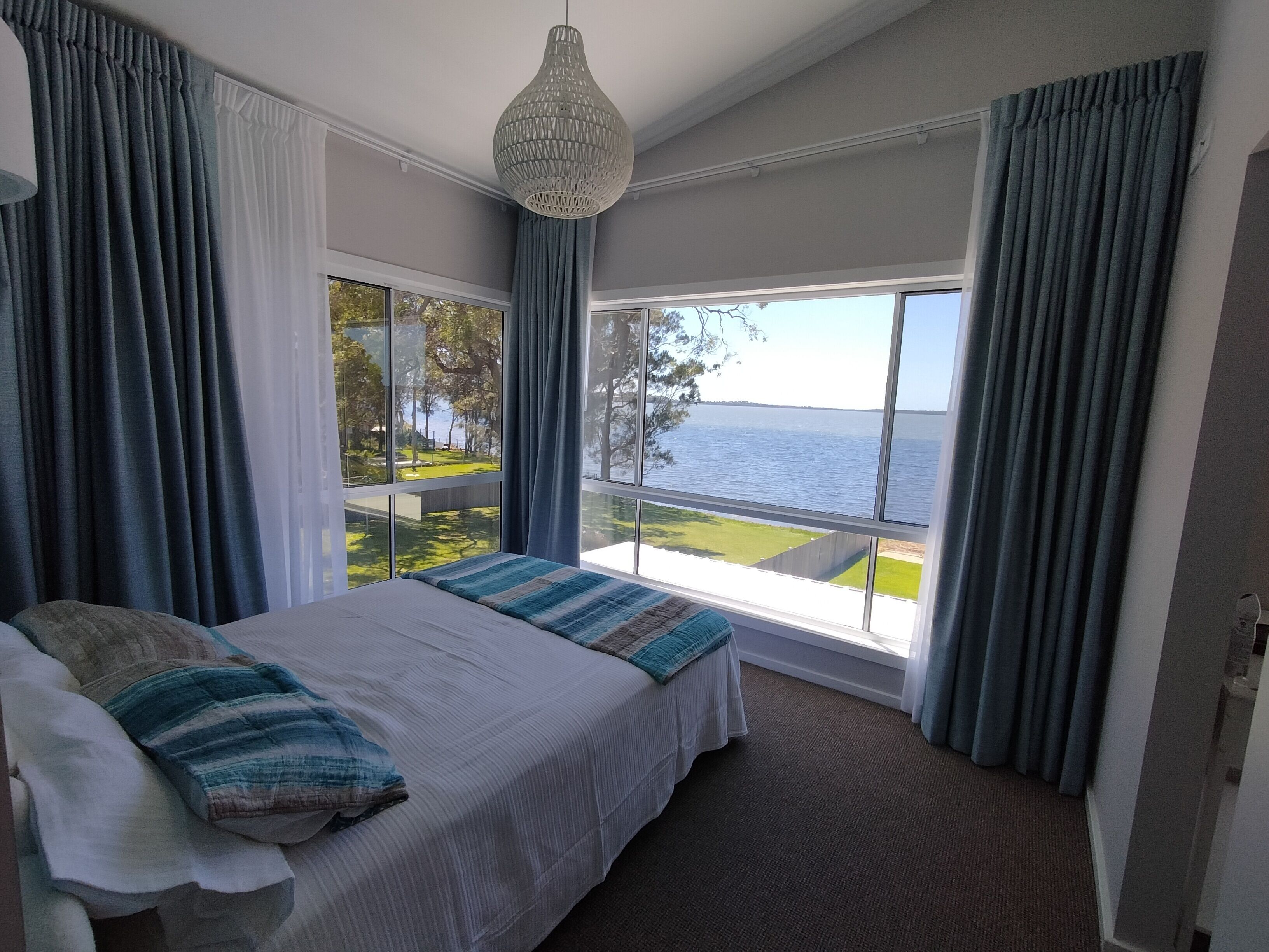 Un dormitorio con una cama grande, vistas al mar y una lámpara colgante.