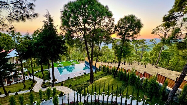 A resort with a swimming pool, manicured lawns, and a variety of trees. - KUMAON ECO RESORTS (Dwarahat)