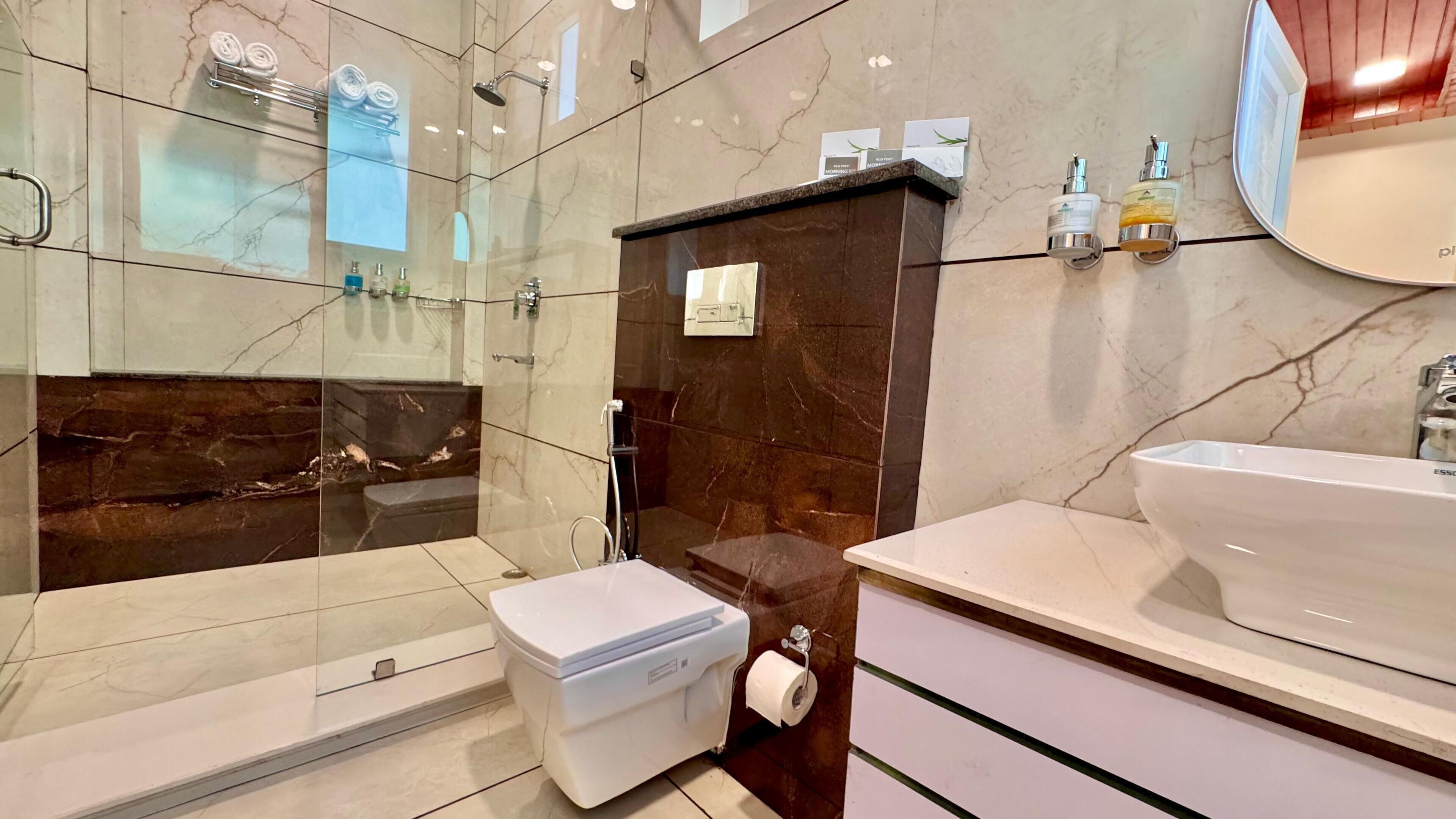 A modern bathroom with a glass-enclosed shower, a white sink, and a marble-tiled wall.