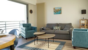 Una sala de estar con un sofá, dos sillones, una mesa de centro y una mesa de comedor.