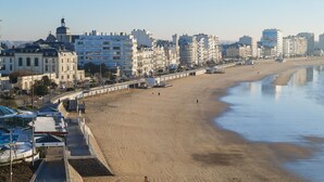 Una playa con un paseo marítimo, edificios y cielo despejado.