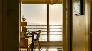 Una habitación con vista al mar, una mesa con sillas, una lámpara y una planta.