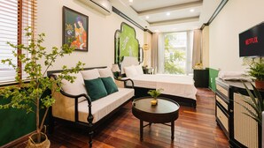 A hotel room with a sofa, a bed, a small table, a TV, and a potted plant. - Sun Clover Boutique Hotel (Hanoi)