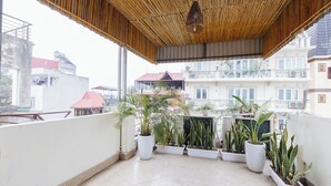 A balcony with potted plants, a bamboo ceiling, and a view of buildings in the background. - Sun Clover Boutique Hotel (Hanoi)