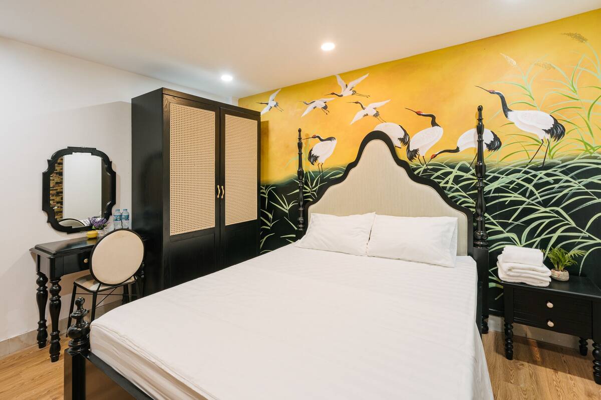 Ein ordentlich eingerichtetes Schlafzimmer mit Bett, Kommode, Spiegel und Wandbild.