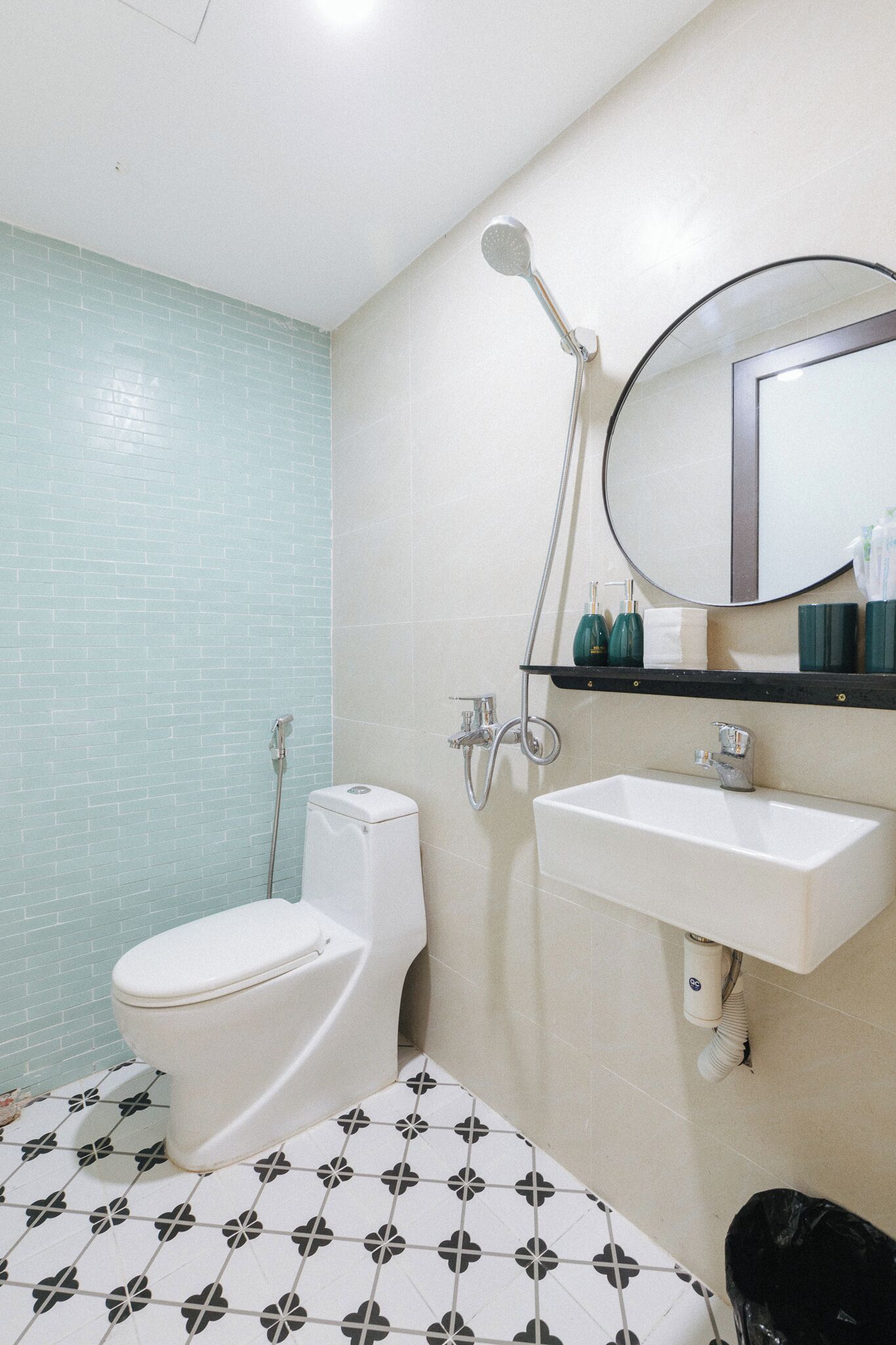 A bathroom with a toilet, a sink, a shower, and a mirror.