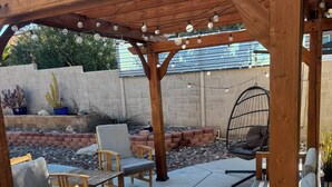 An outdoor patio with wooden furniture, a fire pit, and string lights.