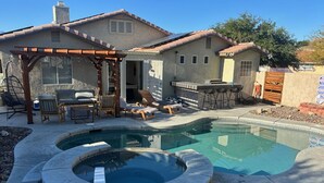 A backyard with a swimming pool, outdoor seating, and a pergola.