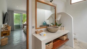 A modern bathroom with a large mirror, a stone basin, and wicker baskets. - Mateo Villa Uluwatu  (Pecatu)