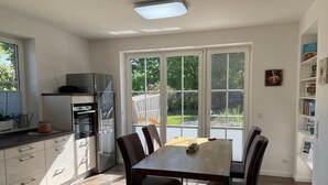 A modern kitchen with a dining area, large windows, and a view of the outdoors.