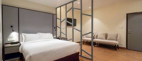 A modern bedroom with a large bed, a nightstand, a sofa, and a partition wall.