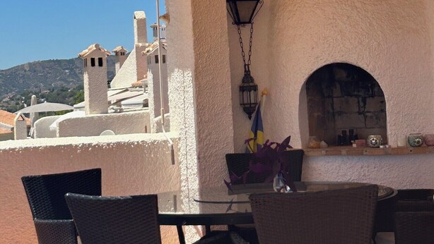 Eine Terrasse im Freien mit Korbstühlen, einem Tisch und einer hängenden Laterne.