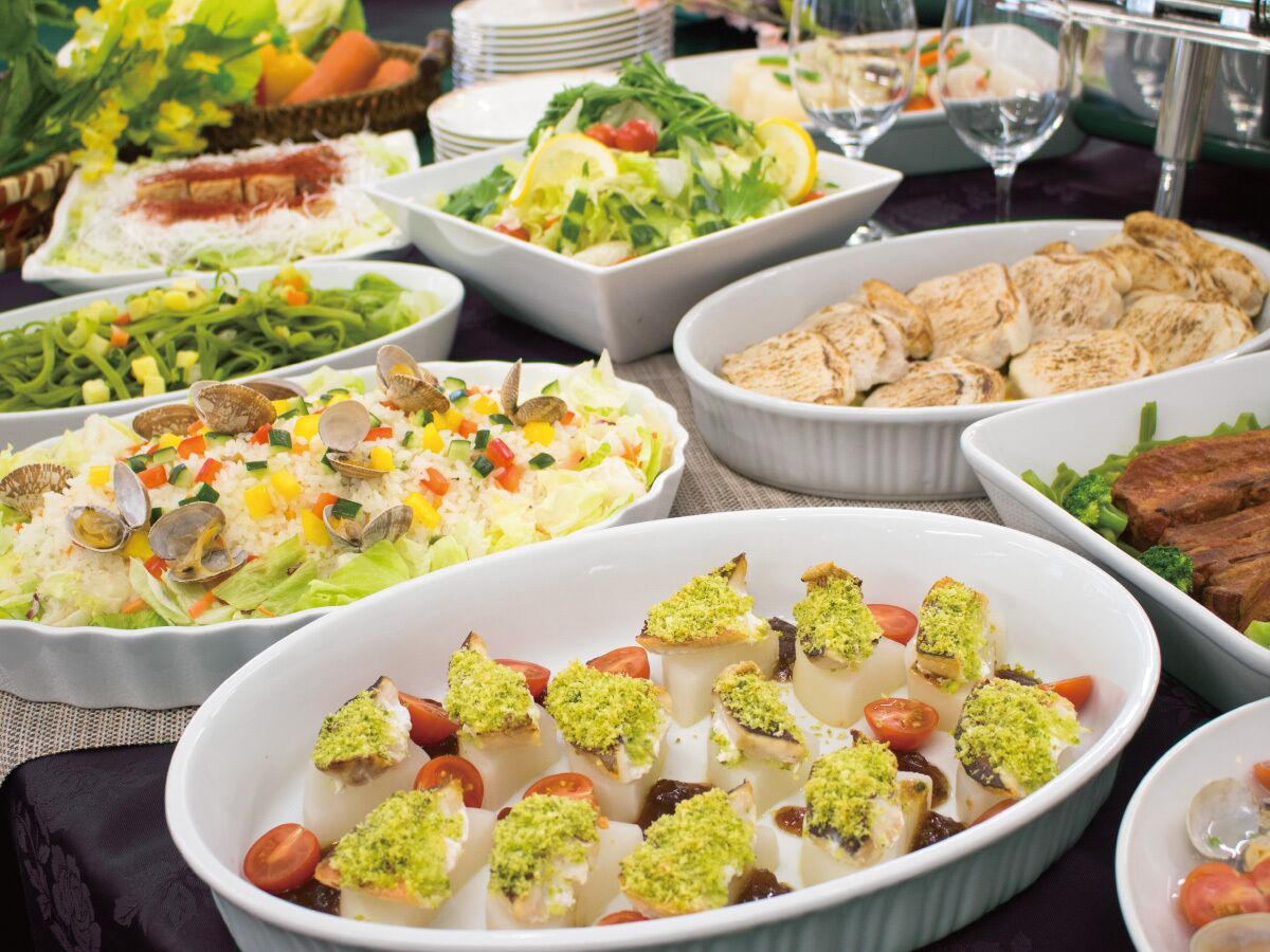 Forskellige retter på et buffetbord, herunder salater, risretter og kød.