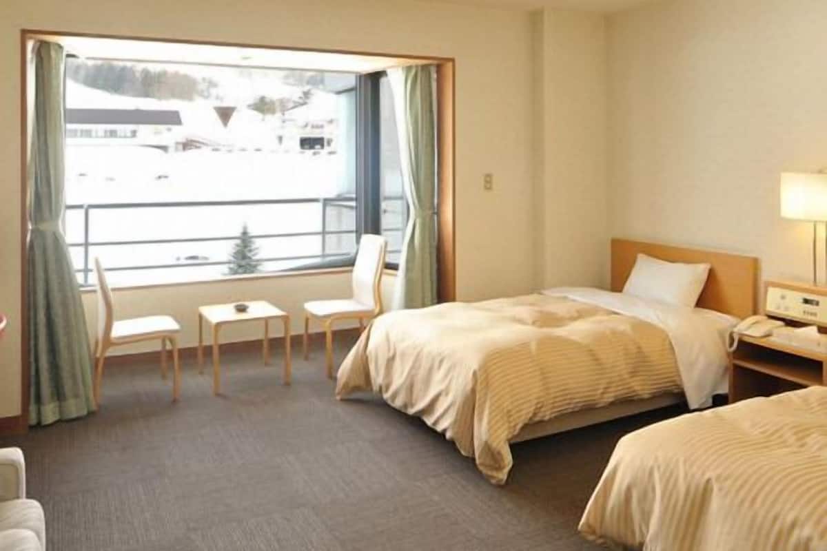 A hotel room with a bed, a desk, a chair, and a window with curtains.