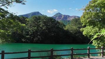 Un camí pavimentat amb una tanca de fusta que condueix a un llac turquesa envoltat d'una frondosa vegetació forestal i muntanyes al fons.