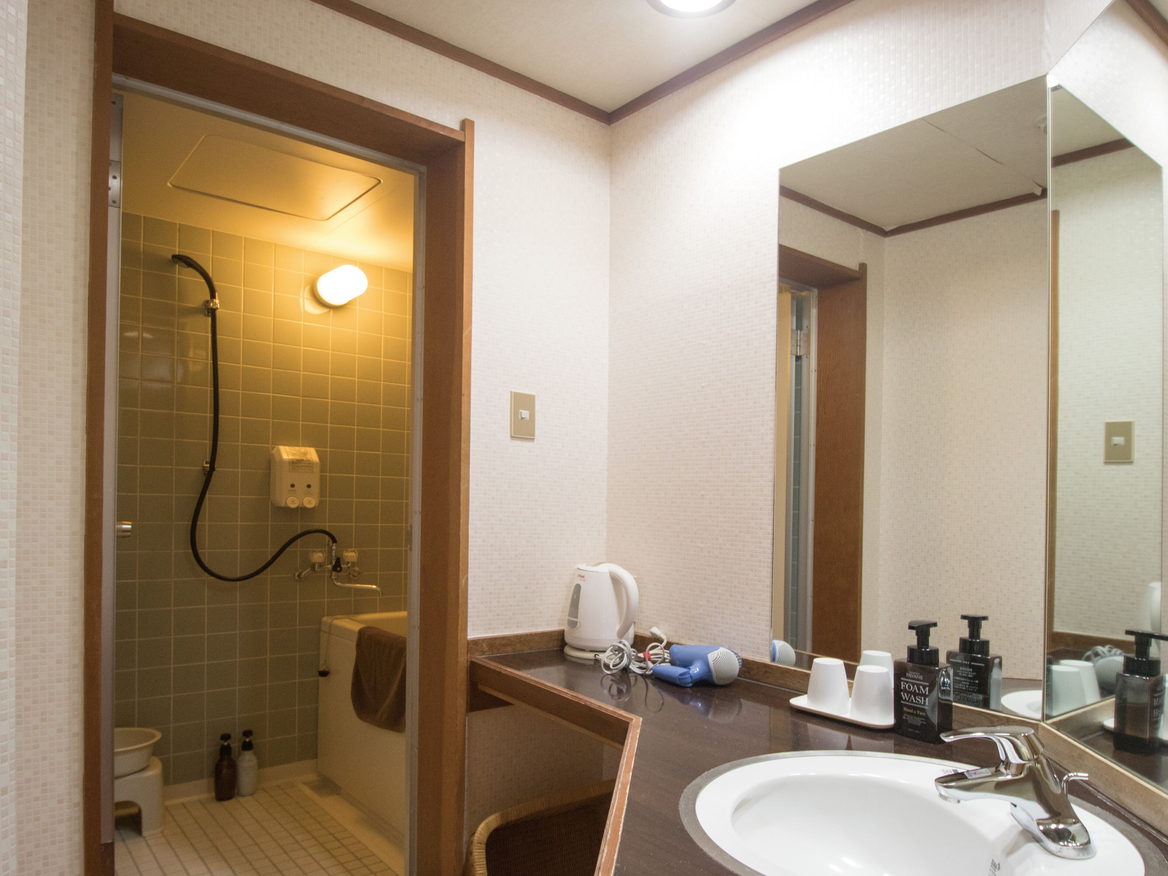 A hotel bathroom with a shower, toilet, sink, and a large mirror.