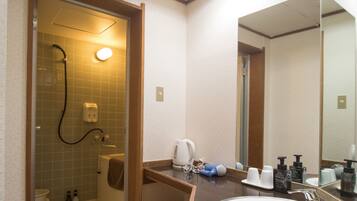 A hotel bathroom with a shower, toilet, sink, and a large mirror.