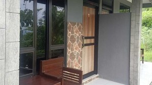 Un espacio al aire libre cubierto con una banca, una mesa, un muro de piedra y una puerta con detalles de madera.
