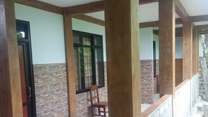 Un corredor espacioso con paredes de piedra y vigas de madera, que conduce a un balcón con baranda de piedra.